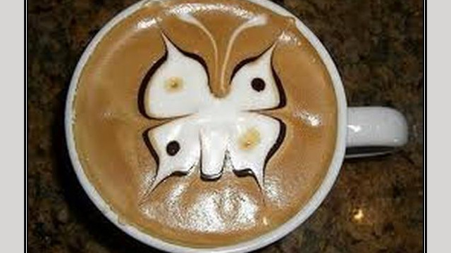 Arte del café con leche: mariposa dibujada en la espuma Arte del café con leche: mariposa dibujada en la espuma