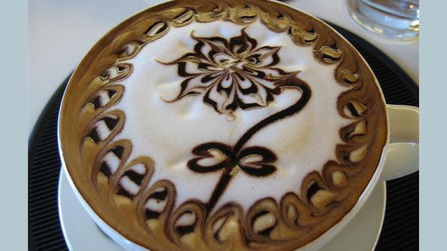 Arte del café con leche: flor dibujada en la espuma Arte del café con leche: flor dibujada en la espuma