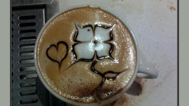 Arte del café con leche: flor dibujada en la espuma Arte del café con leche: flor dibujada en la espuma