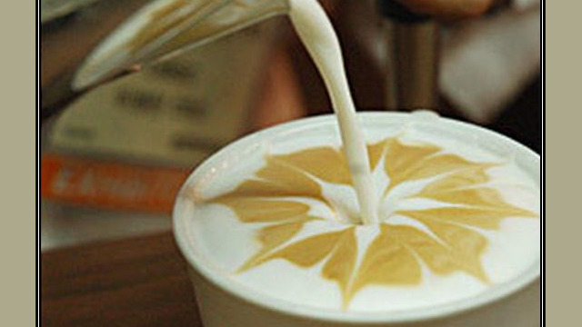 Arte del café con leche: flor dibujada en la espuma Arte del café con leche: flor dibujada en la espuma