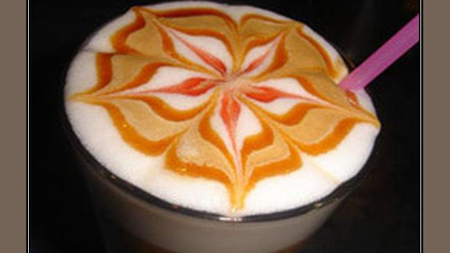 Arte del café con leche: motivo floral en colores, dibujado en la espuma Arte del café con leche: motivo floral en colores, dibujado en la espuma