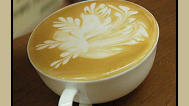 Arte del café con leche: flor blanca dibujada en la espuma Arte del café con leche: flor blanca dibujada en la espuma